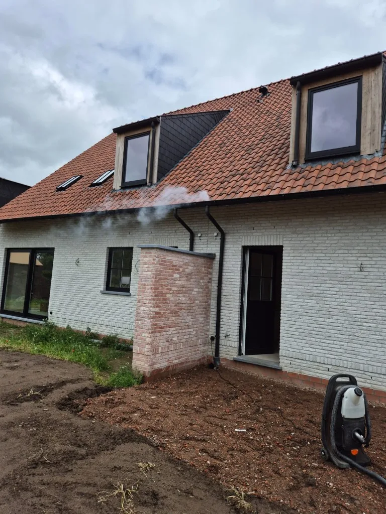 Rooktest bij nieuwbouw met rook uit de regenpijp en rookmachine op de werf