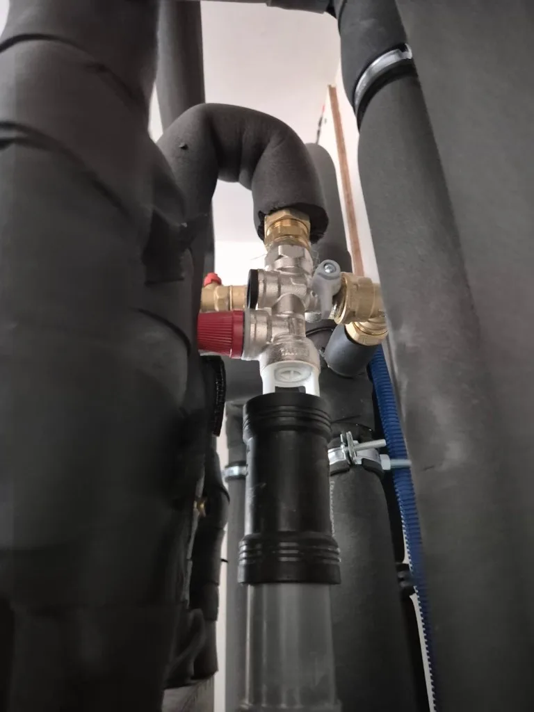 Technische waterinstallatie met geïsoleerde leidingen en veiligheidsklep tijdens een waterkeuring